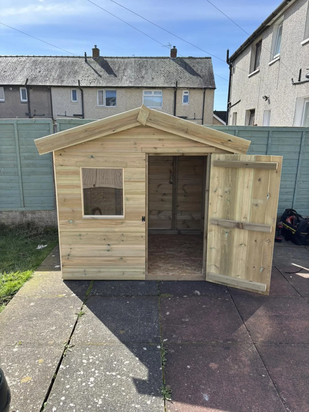 Small timber apex-roof shed with a window and an open door