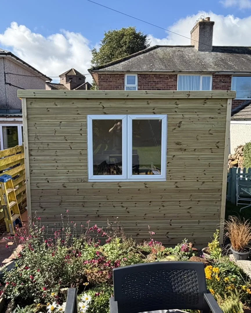 Flat-roof timber garden building with a white-framed window