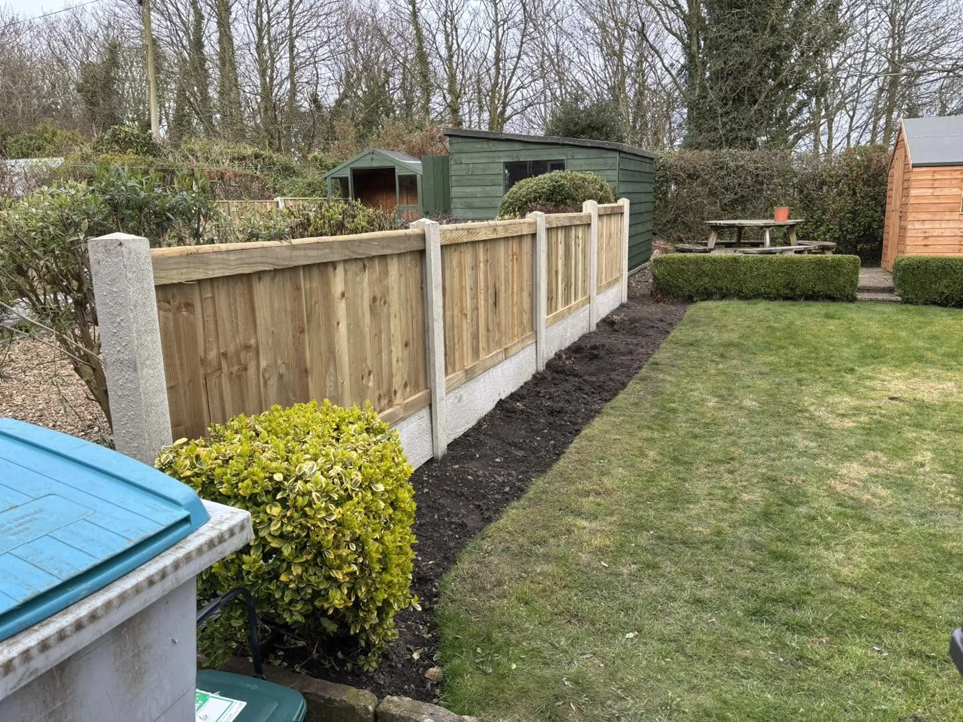 Timber fence panels with concrete posts alongside a garden lawn